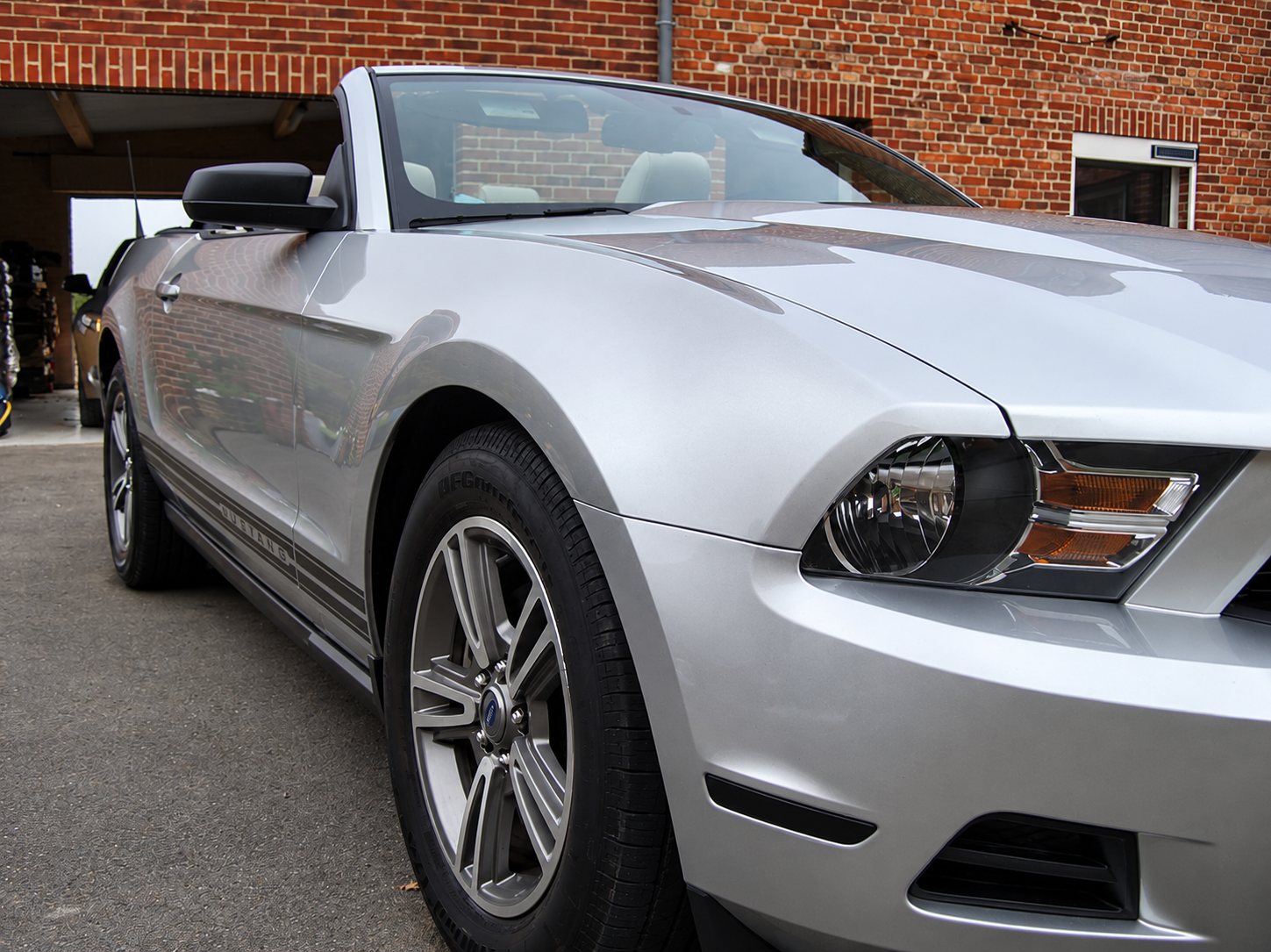 Ford Mustang cabriolet grise devant un mur de briques, après nettoyage