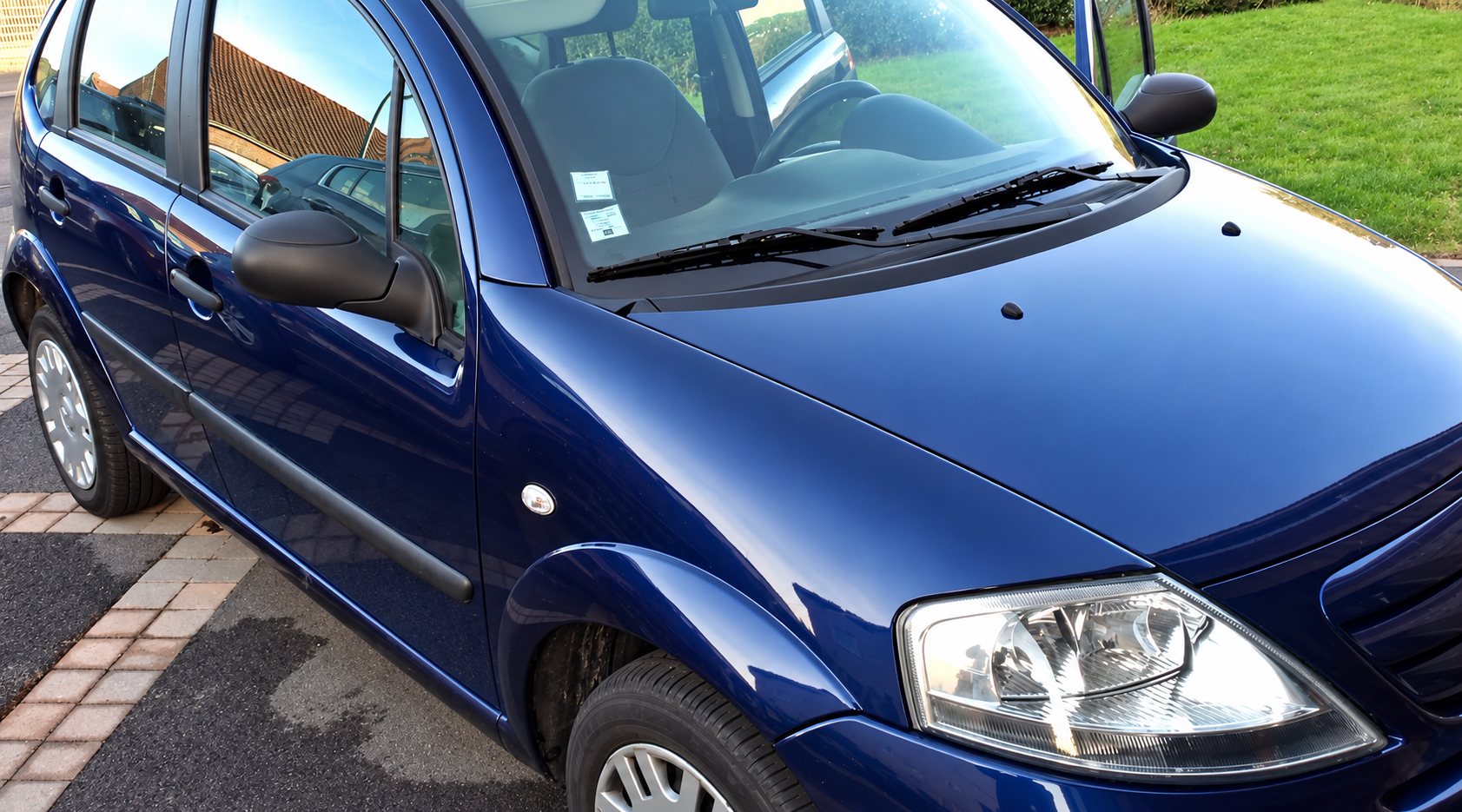 Citroën C3 bleue avant nettoyage, près d’une pelouse