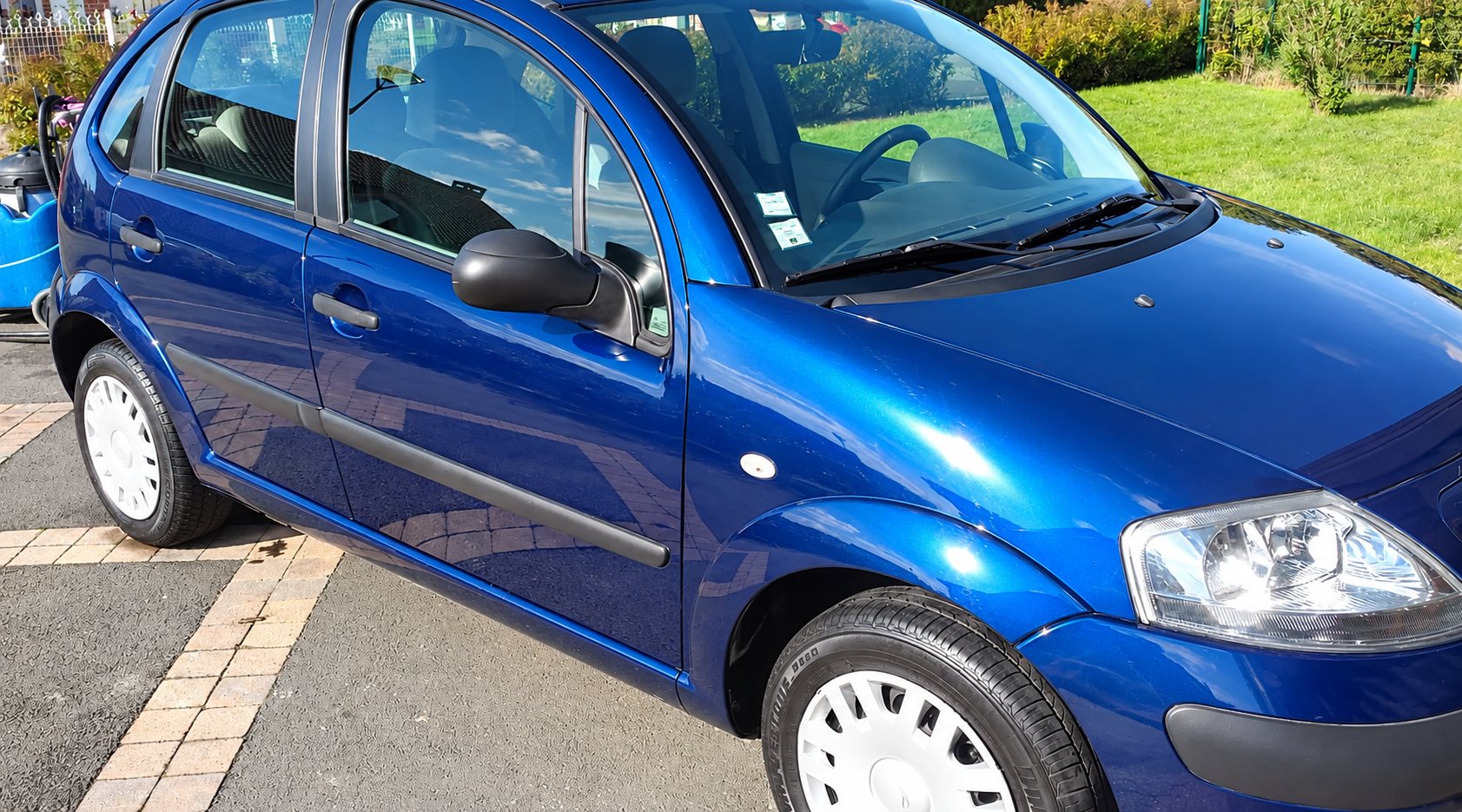 Citroën bleue brillante, nettoyée à la vapeur, sur une allée pavée